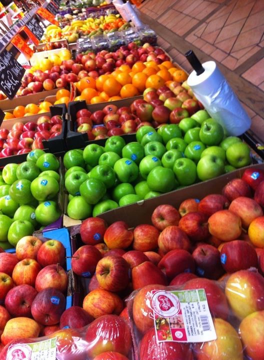 Crates of green and red apples and oranges on the fruit display