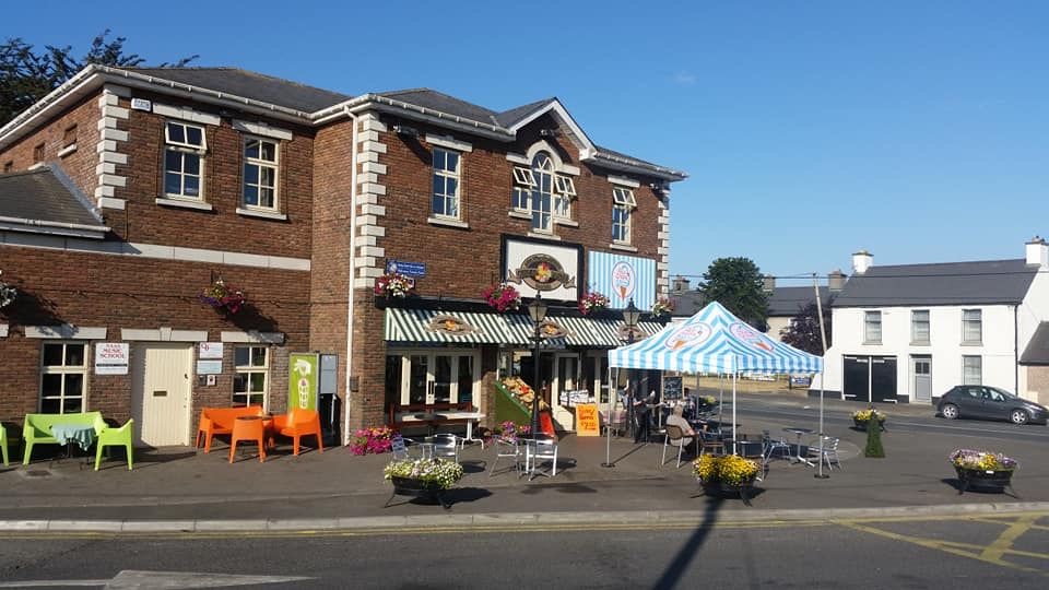 Swans on the Green on a sunny day, with hanging baskets, colourful outdoor seating and a striped gazebo