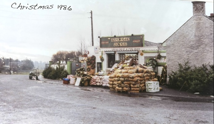 Archive photograph marked Christmas 1986: a small shop signed Fairgreen Stores, Fresh Fruit and Veg Daily, with sacks of potatoes and Christmas trees outside