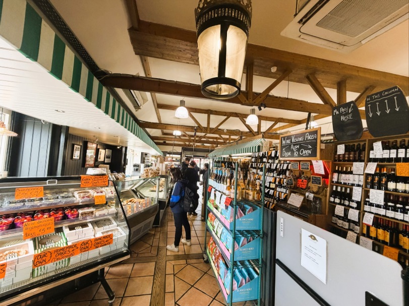 Inside the shop: timber beams, a hanging lantern, the deli counter and shelves of wine