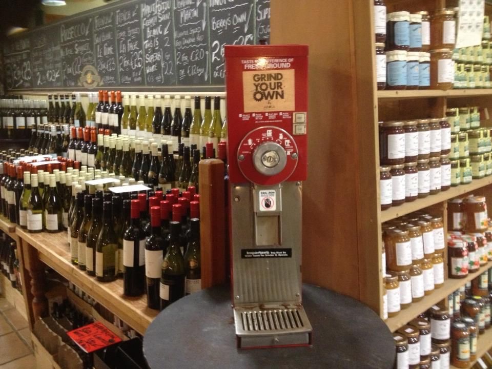 Shelves of wine and jars of preserves beside a red grind-your-own coffee machine